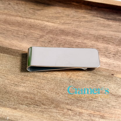 Silver money clip on a wooden surface with 'Cramer's Custom Creations' branding.