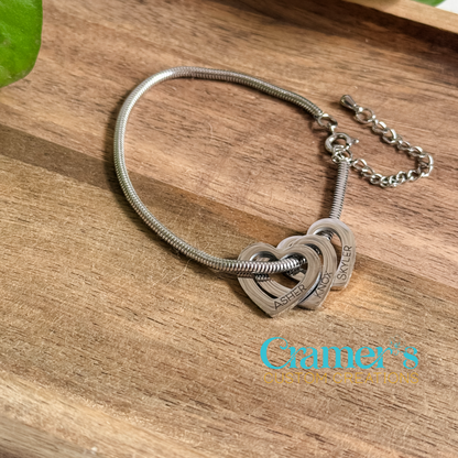 Silver bracelet with heart-shaped charms on a wooden surface, featuring 'Cramer's Custom Creations' branding.