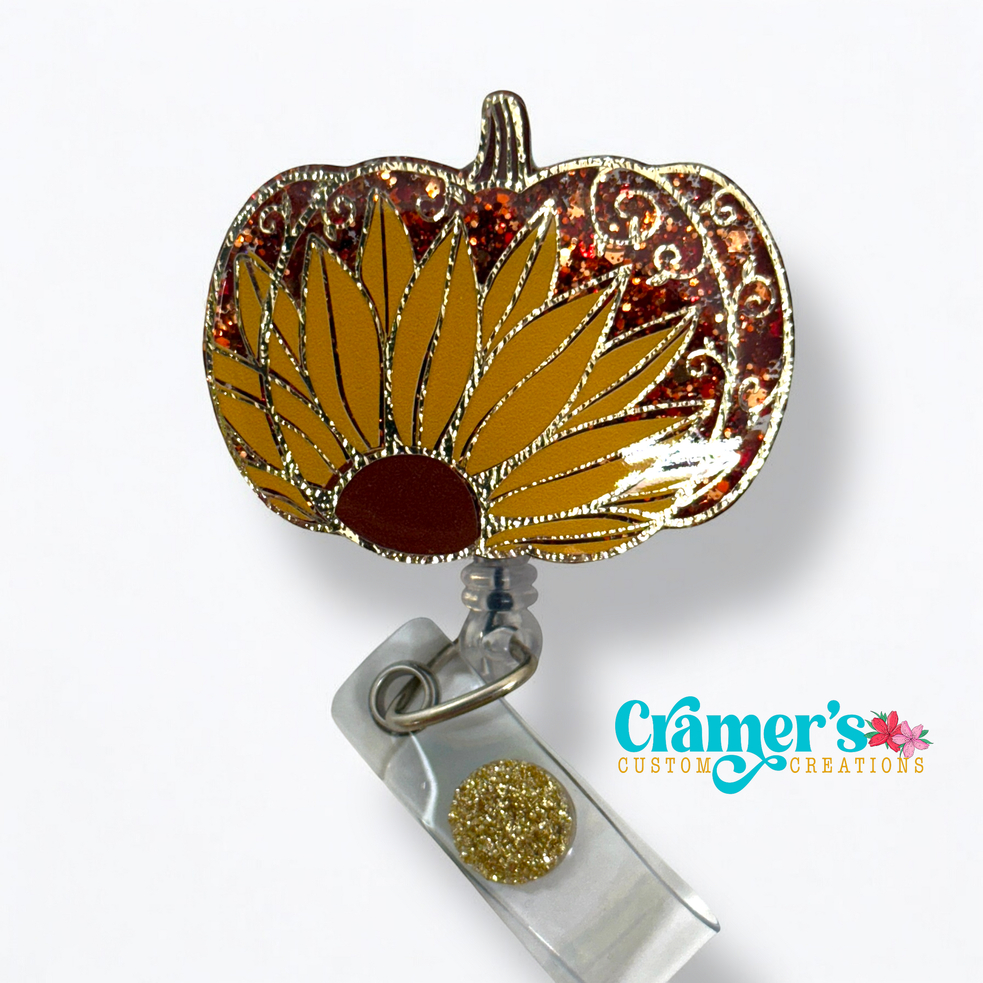 a pumpkin badge reel decorated with a sunflower and a gold filigree