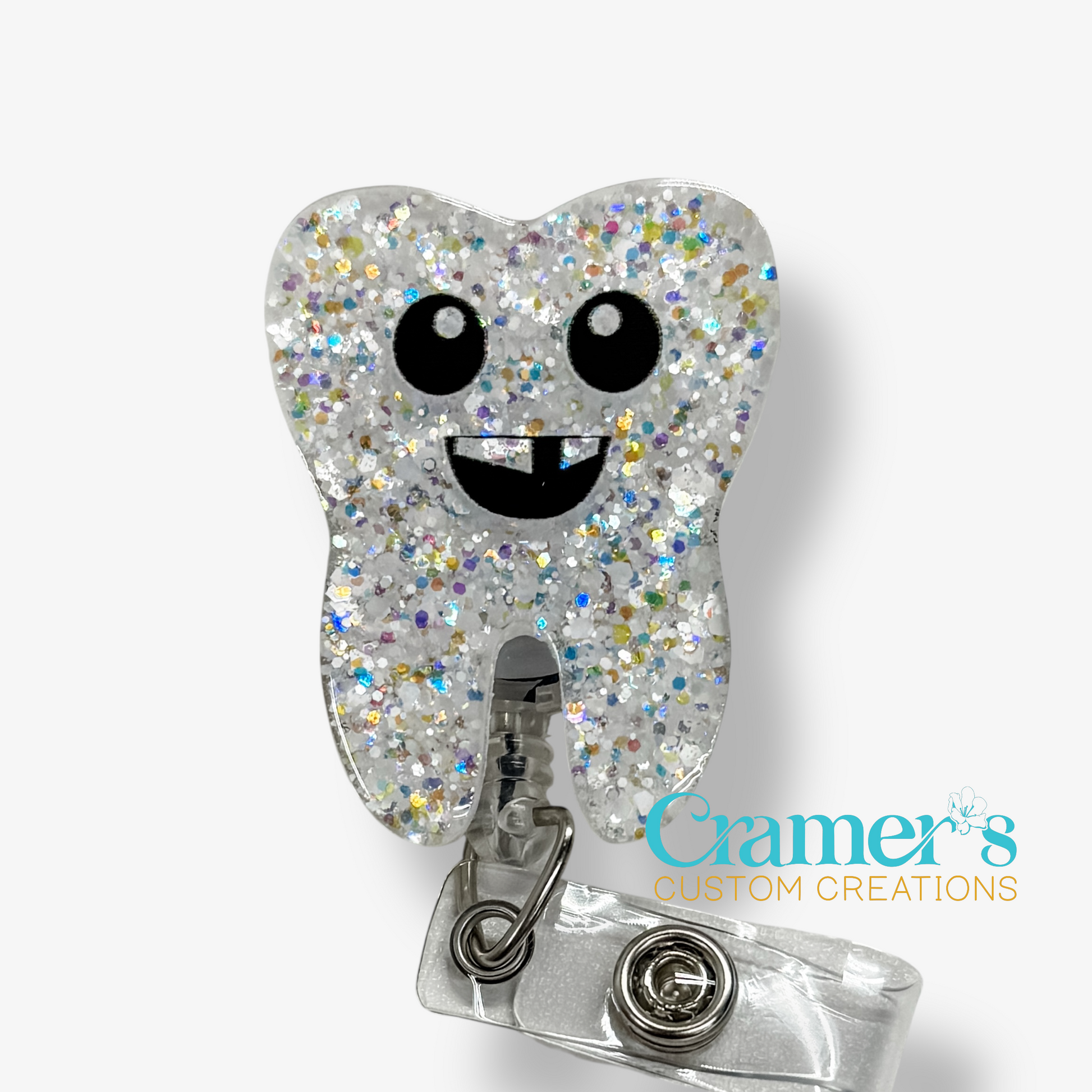 Glittery tooth-shaped badge holder with a smiley face on a white background, featuring the brand 'Cramer's Custom Creations'.