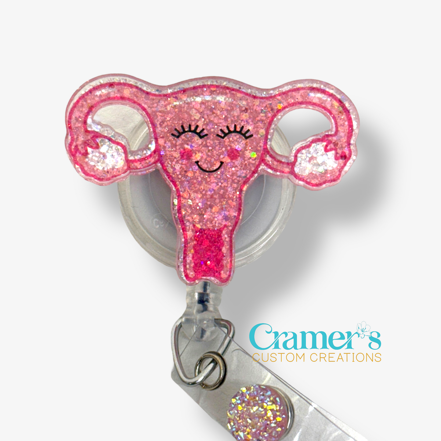 pink glittery uterus badge reel with a smile on its face