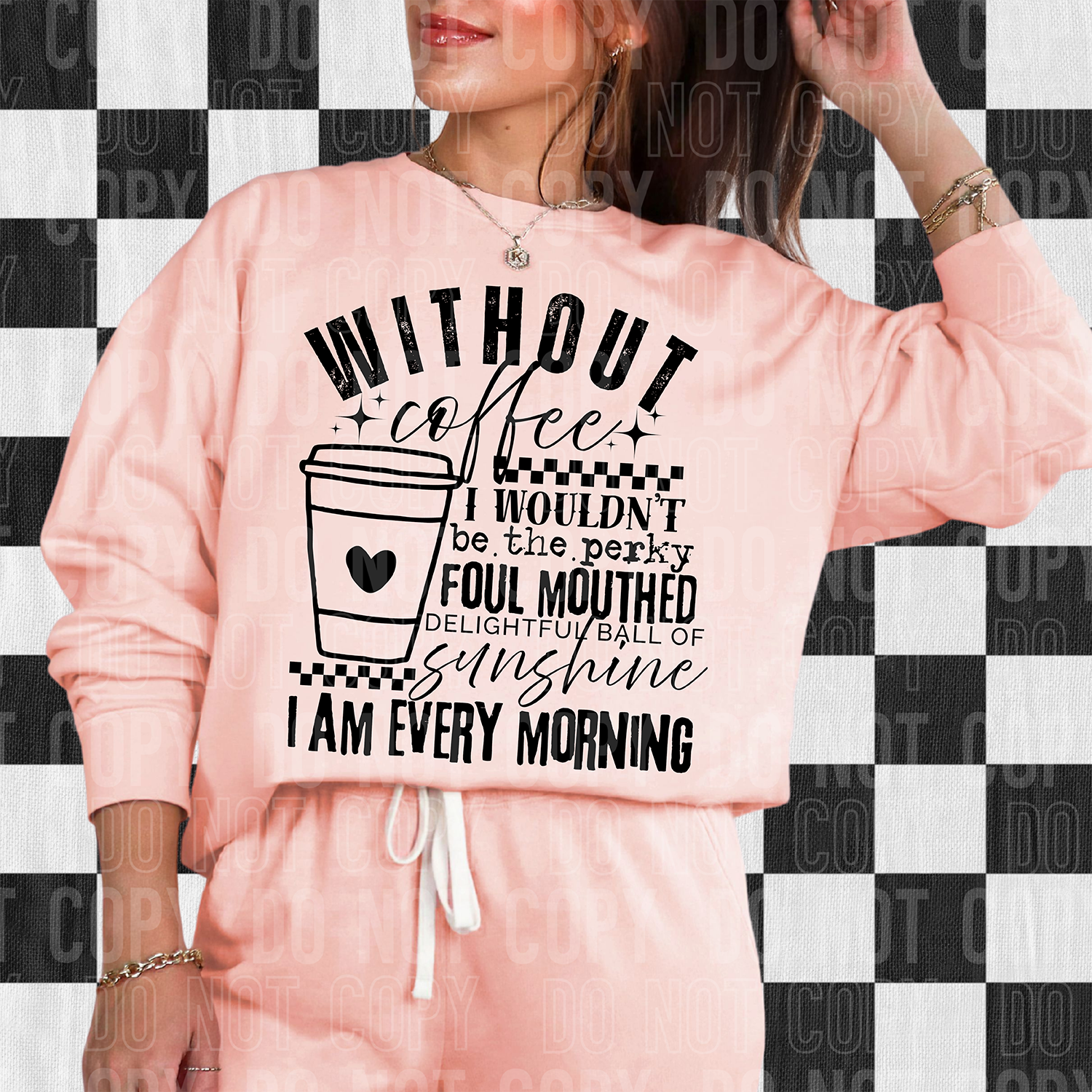 Person wearing a pink sweatshirt with a coffee-themed quote on a checkered background