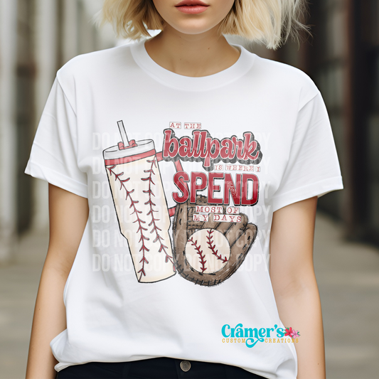 woman wearing white tshirt with a baseball stanley style tumbler, a baseball mitt, and says at the ballpark is where I spend most of my days