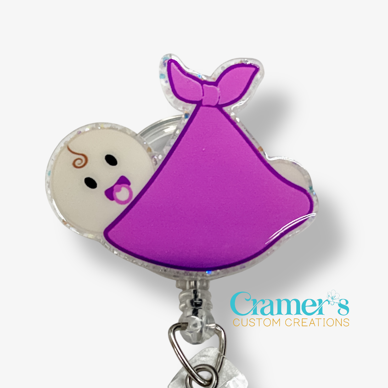 Baby character badge reel with purple dress on a white background, featuring 'Gamer's Custom Creations' logo.