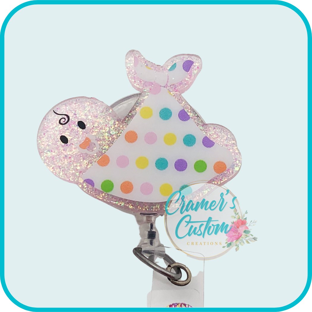 badge reel of a glittery pink baby wrapped in a polka dot blanket