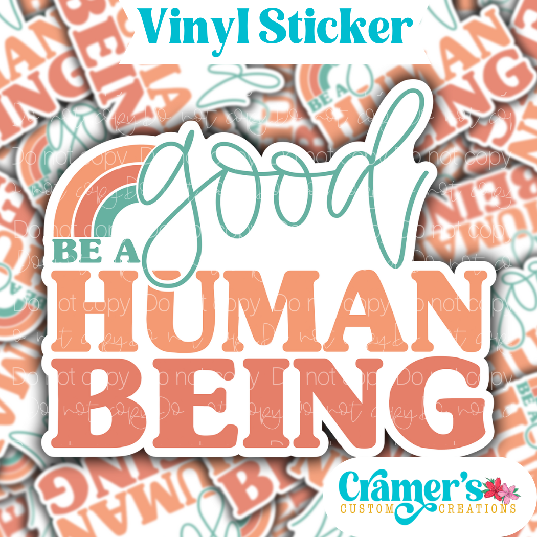 Sticker laying flat that says be a good human being on a background of the same sticker stacked up
