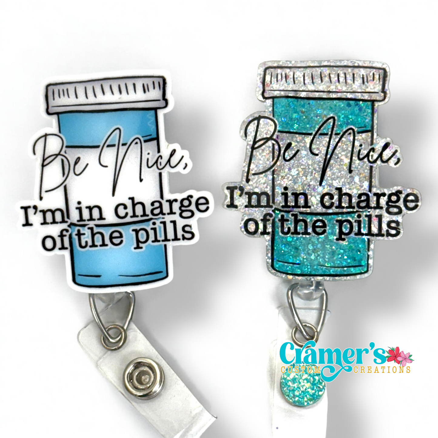 2 badge reels showing a glitter and a non glitter option of a badge with a pill bottle with the words be nice, i'm in charge of the pills