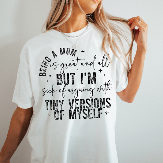 woman wearing a white tshirt with a graphic that says bring a mom is great and all but i'm ti9red of arguing with tiny versions of myself in black