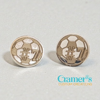 Pair of silver soccer ball earrings with '#7' on a light gray background, branded 'Cramer's Custom Creations'.