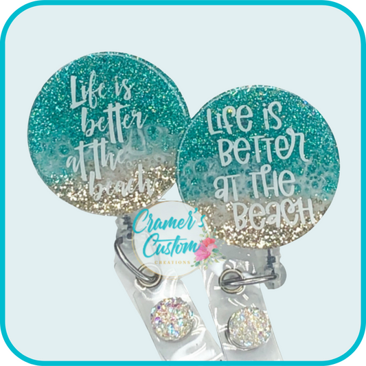 circle badge with a beachy color theme says life is better at the beach in two fonts