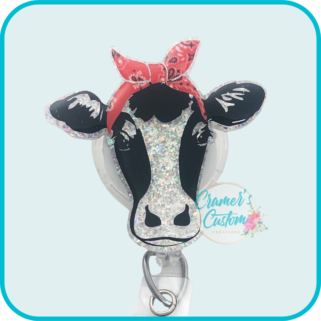 cow with red bandana badge reel on a light teal background