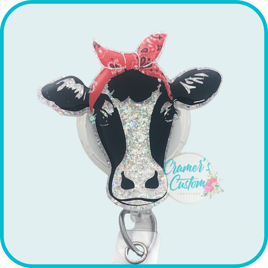 cow with red bandana badge reel on a light teal background