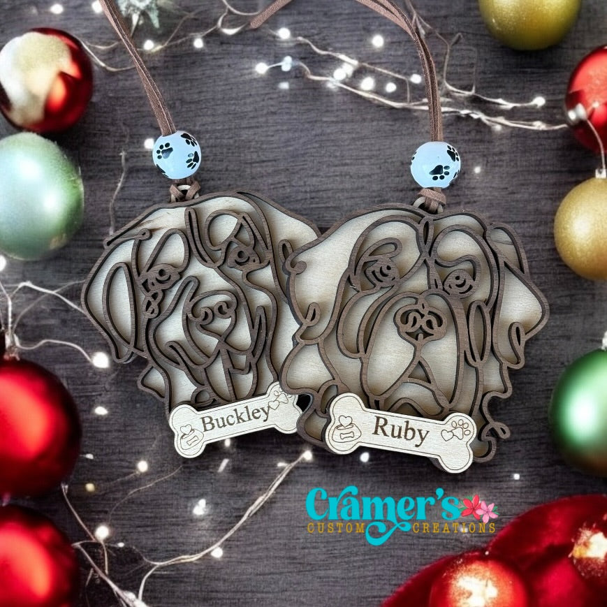 two dog ornaments on a wood background with christmas decor and lights around