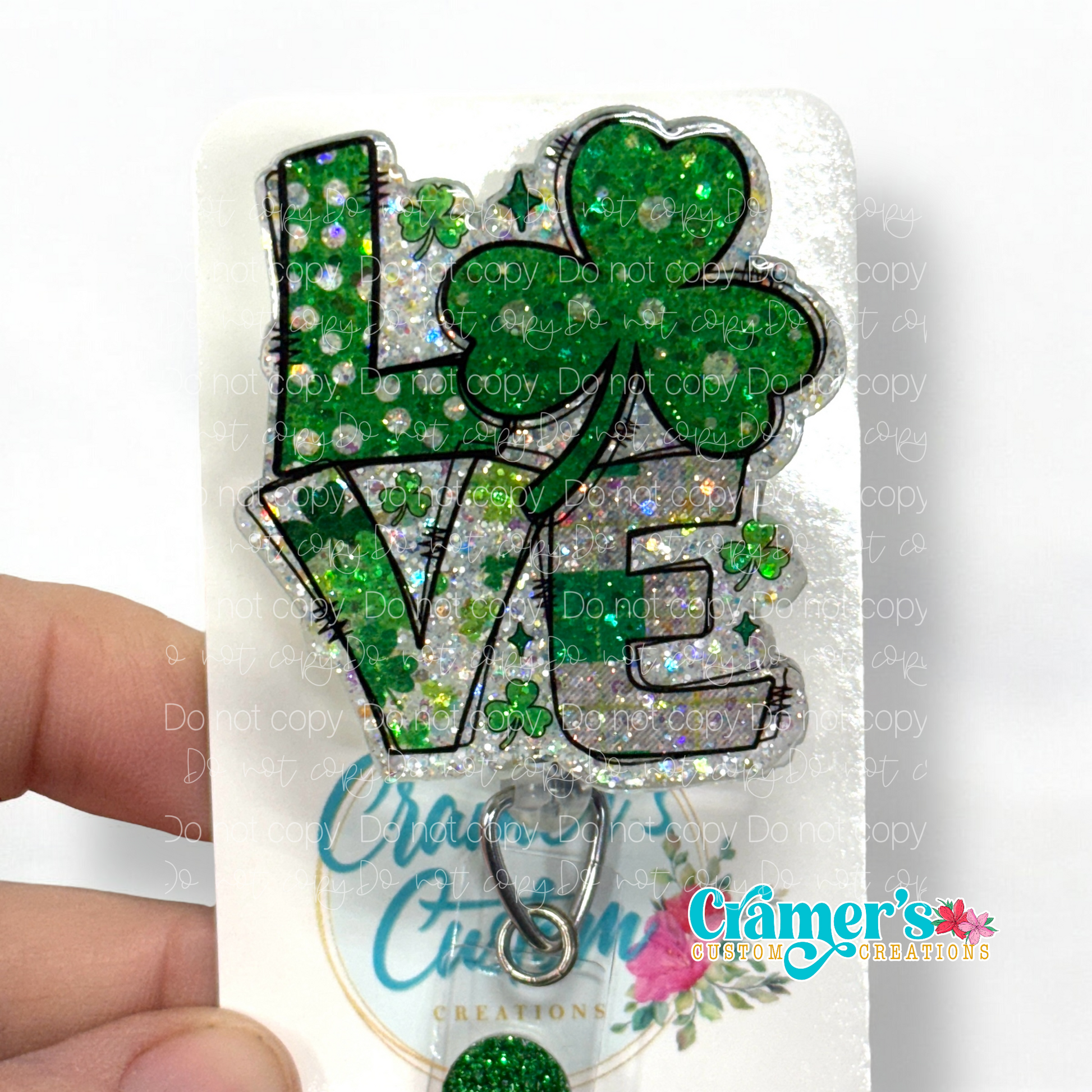 badge reel showing a glitter glitter option of a badge with the word love with a shamrock being the O