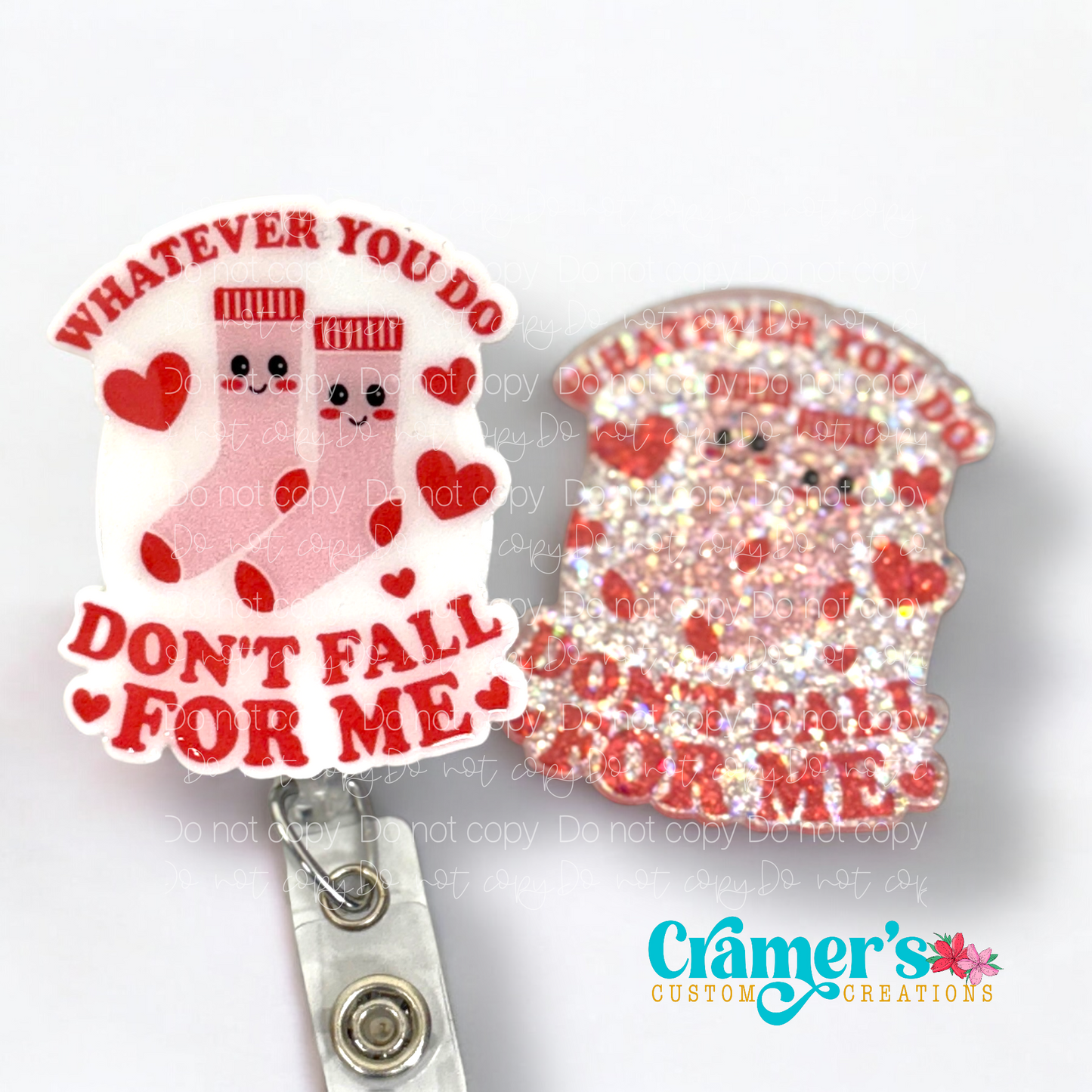 2 badge reels showing a glitter and a non glitter option of a badge with pink socks and hearts that says whatever you do, don't fall for me