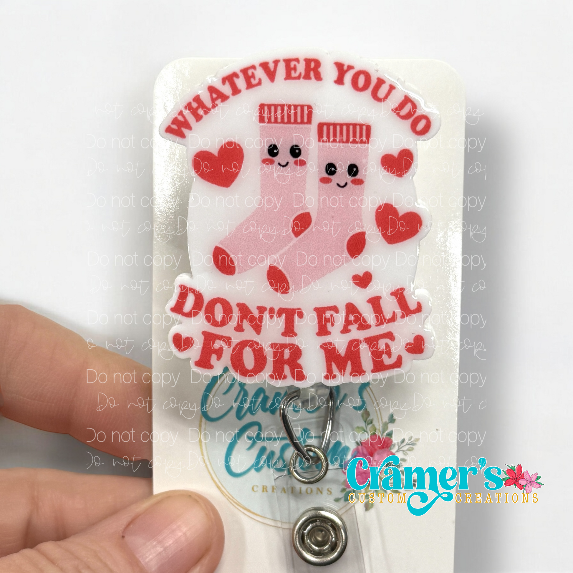 badge reel showing a non glitter option of a badge with pink socks and hearts that says whatever you do, don't fall for me