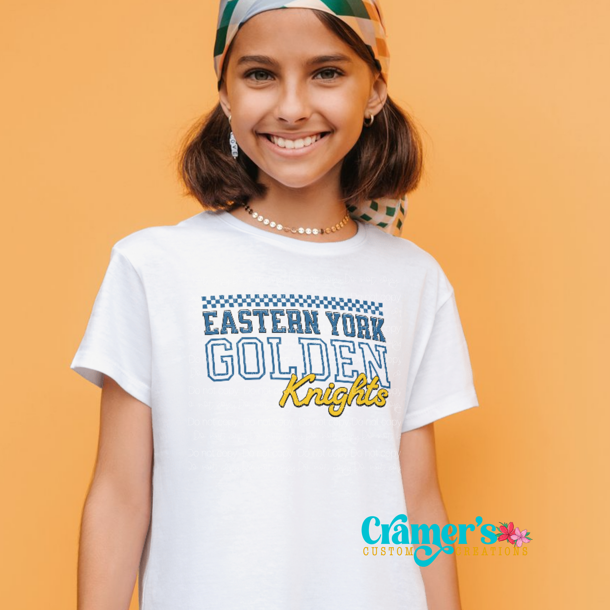 A young person wearing a white t-shirt with 'Eastern York Golden Knights' text printed on the front.