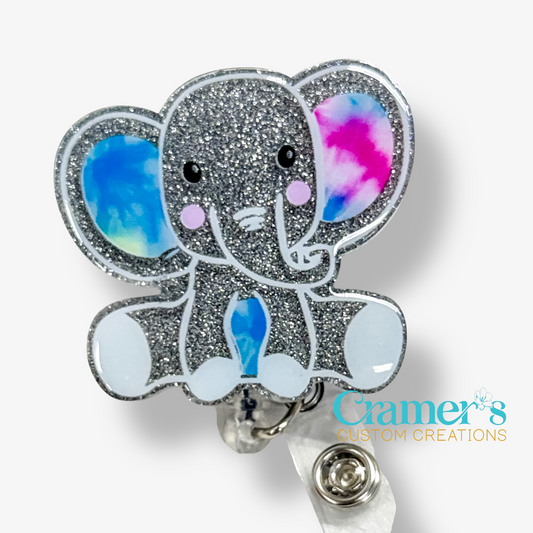 Glittery elephant-shaped badge holder with watercolor ears on a white background, featuring 'Cramer's Custom Creations' logo.