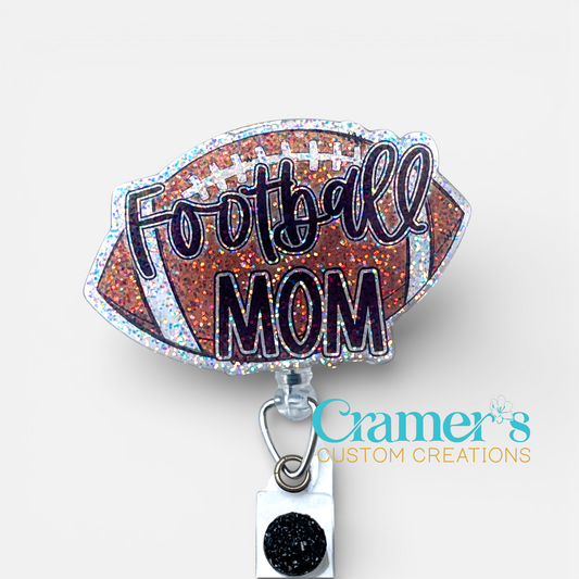 glitter badge reel shaped like a football with football mom on it