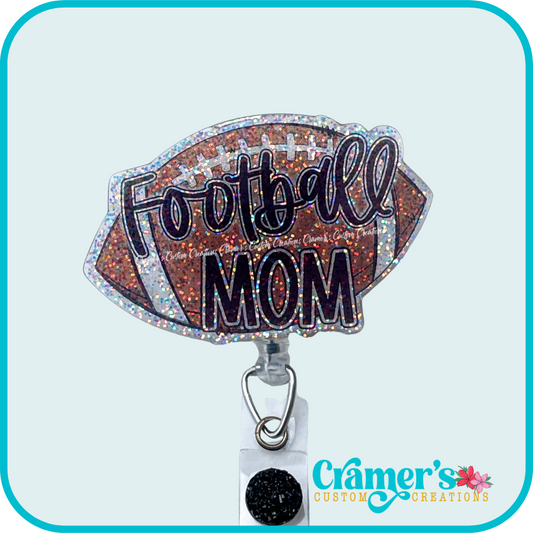 glitter badge reel shaped like a football with football mom on it