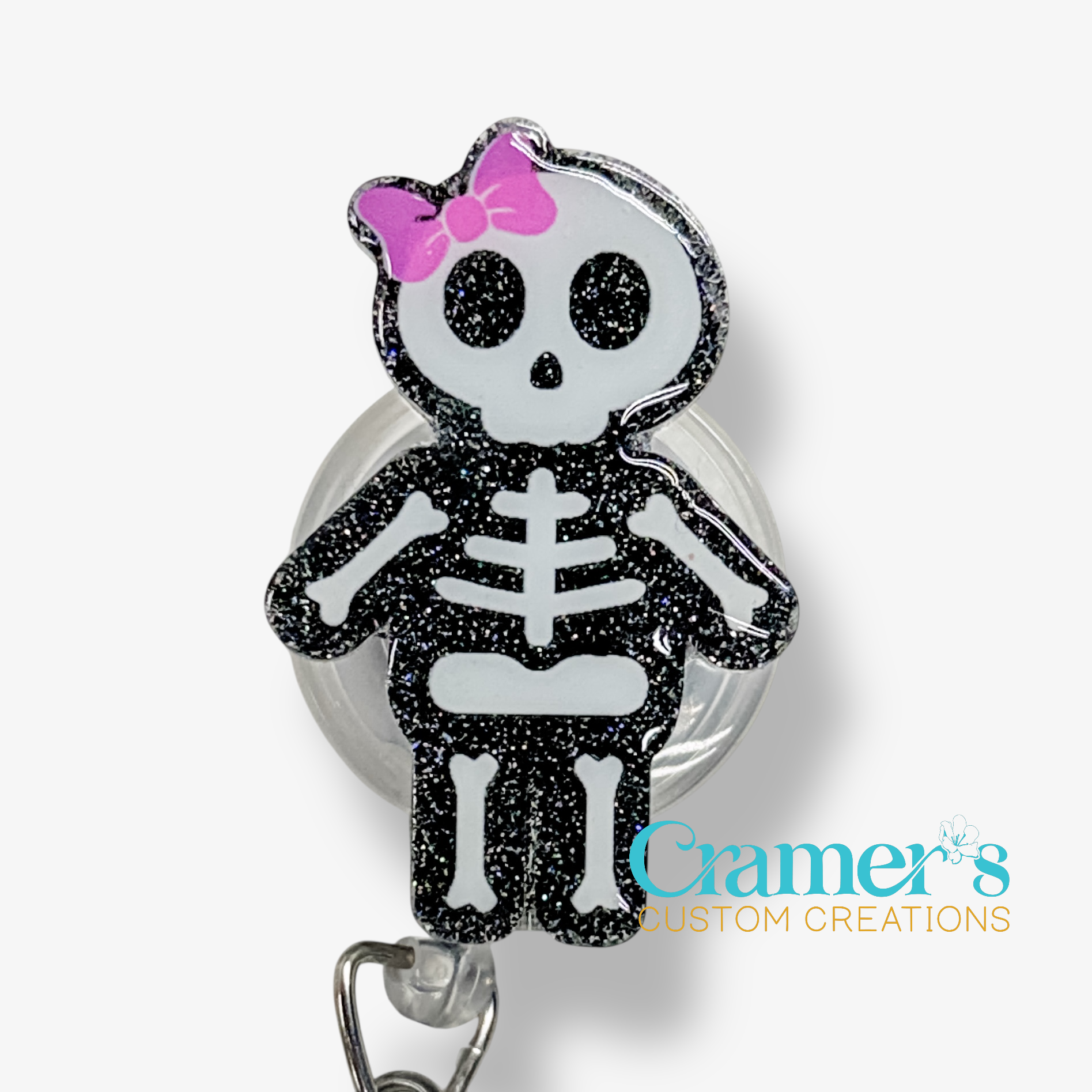 Skeleton character with a pink bow on a badge holder against a white background, branded 'Cramer's Custom Creations'.