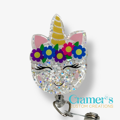 Unicorn-shaped badge holder with colorful flowers and a smiling face on a white background, branded 'Cramer's Custom Creations'.