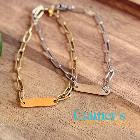 Two gold and silver chain bracelets on a wooden surface with 'Cramer's' branding.