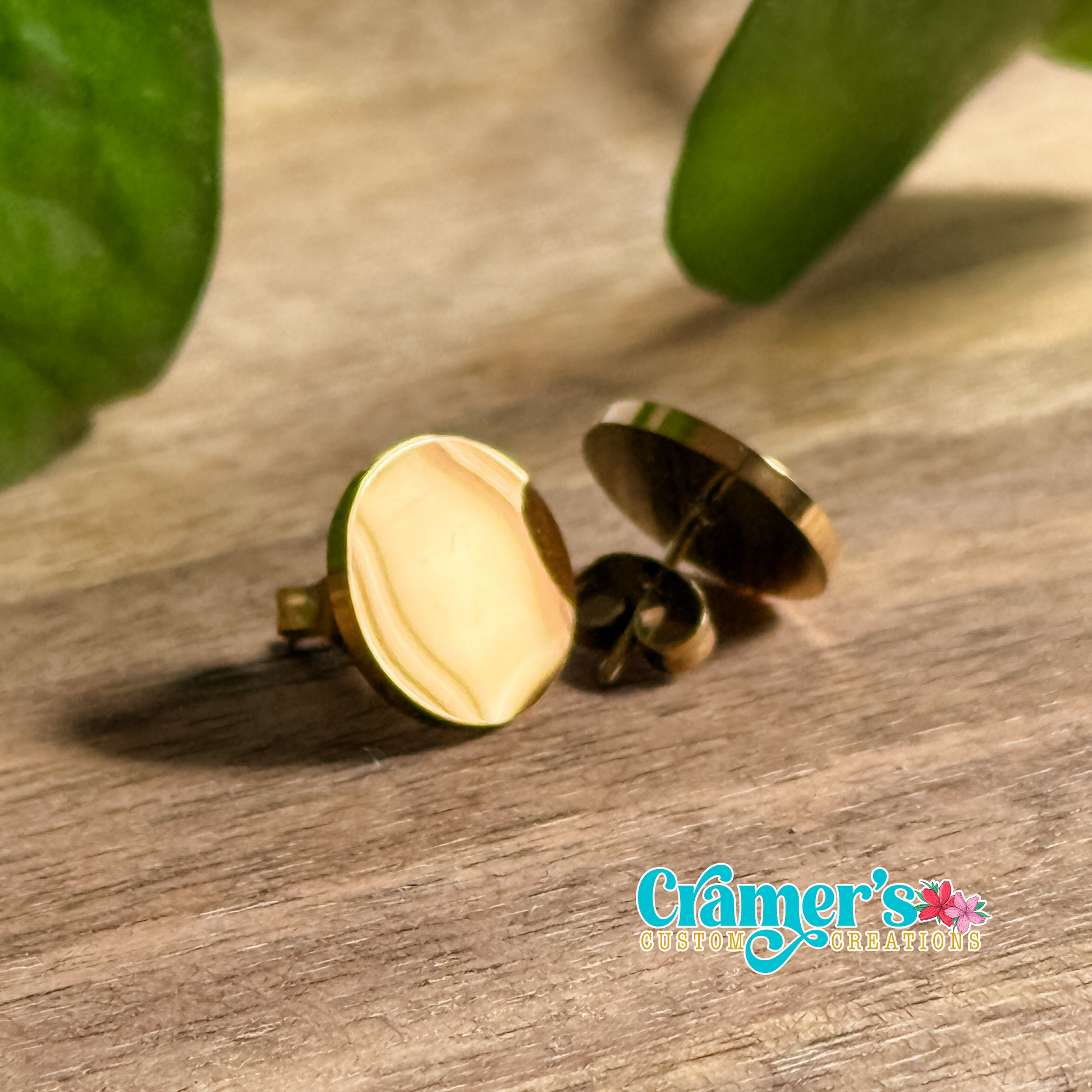 a pair of gold circle stud earrings on a wood background