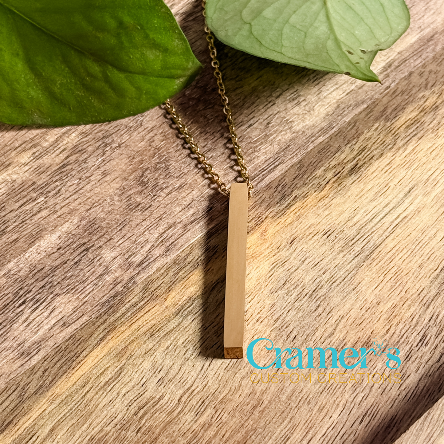 a gold vertical bar necklace on a wood background