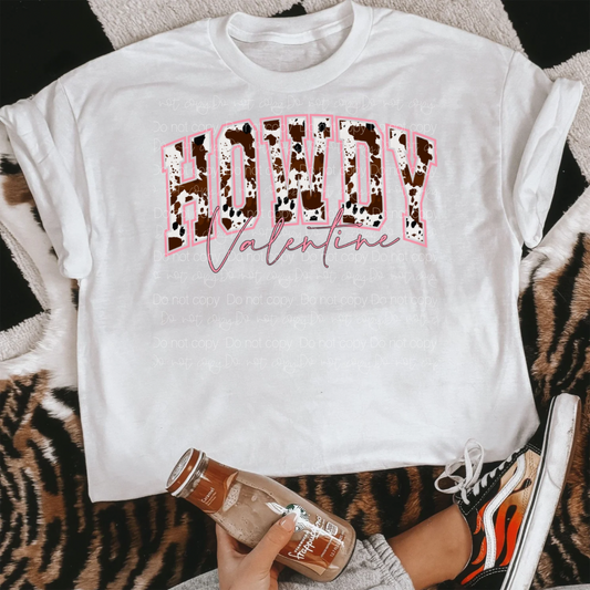 White shirt laying flat with the words howdy valentine.  The howdy is in cow print