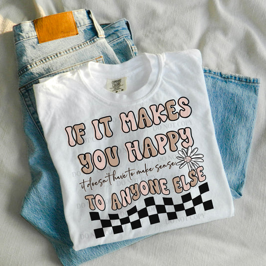 A white t-shirt with pink and black text and floral design, placed on a surface with blue jeans and a brown belt in the background.