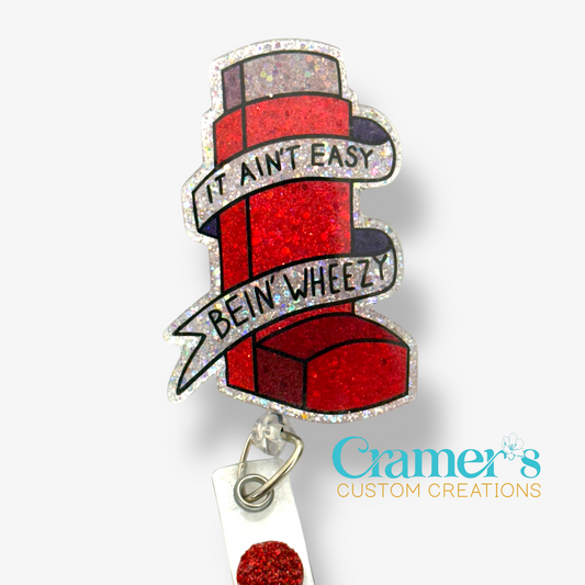 Red glitter inhaler badge reel that says it aint easy being wheezy