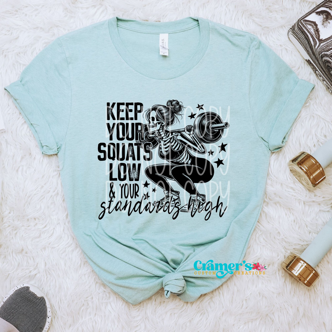 a blue shirt flat lay with a skeleton doing a squat saying keep your squats low and your standards high