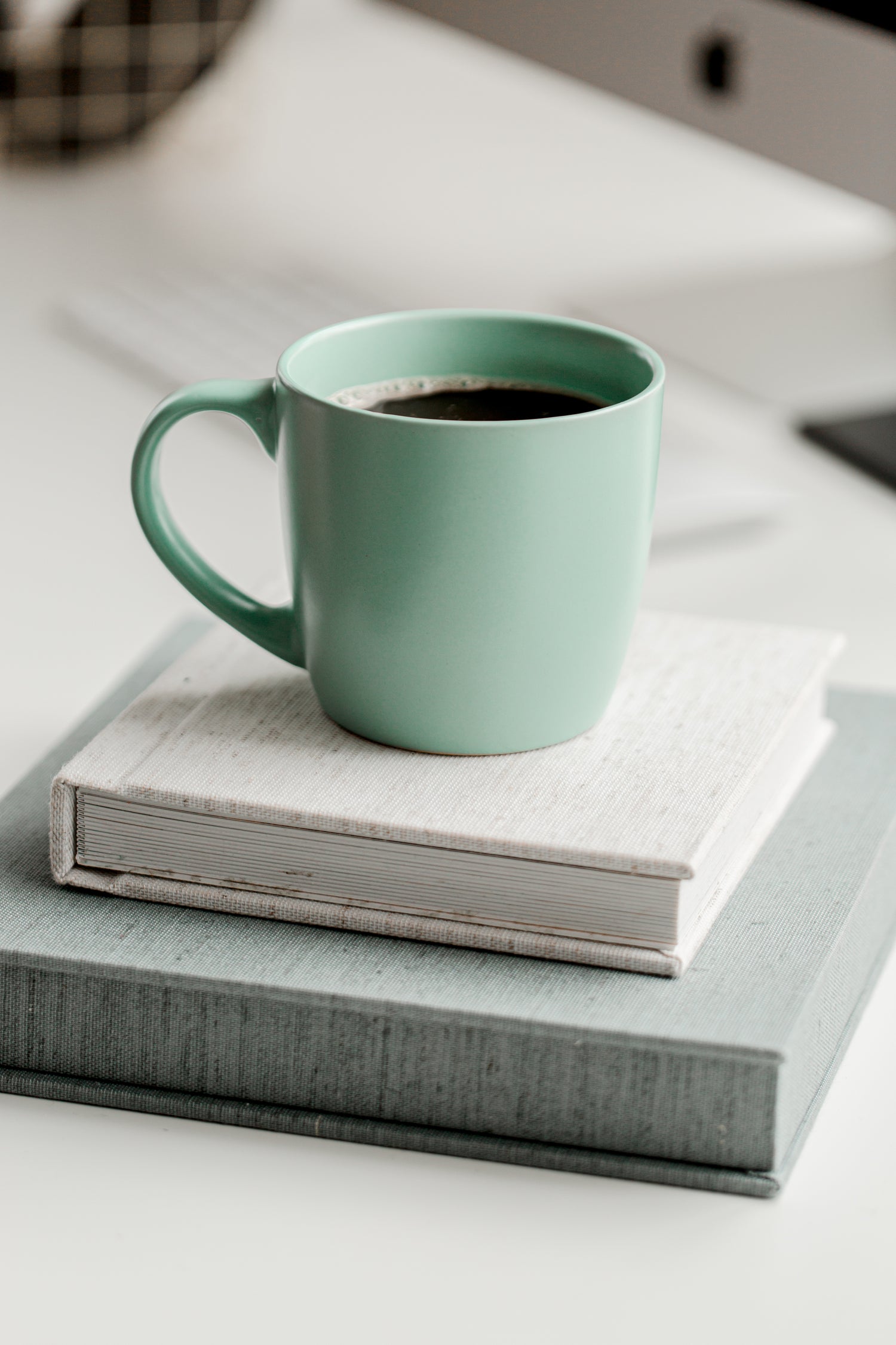 mint green coffee cup sitting on two books