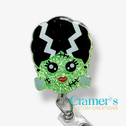Character-shaped badge holder with green face and black hair on a white background, featuring 'Cramer's Custom Creations' logo.