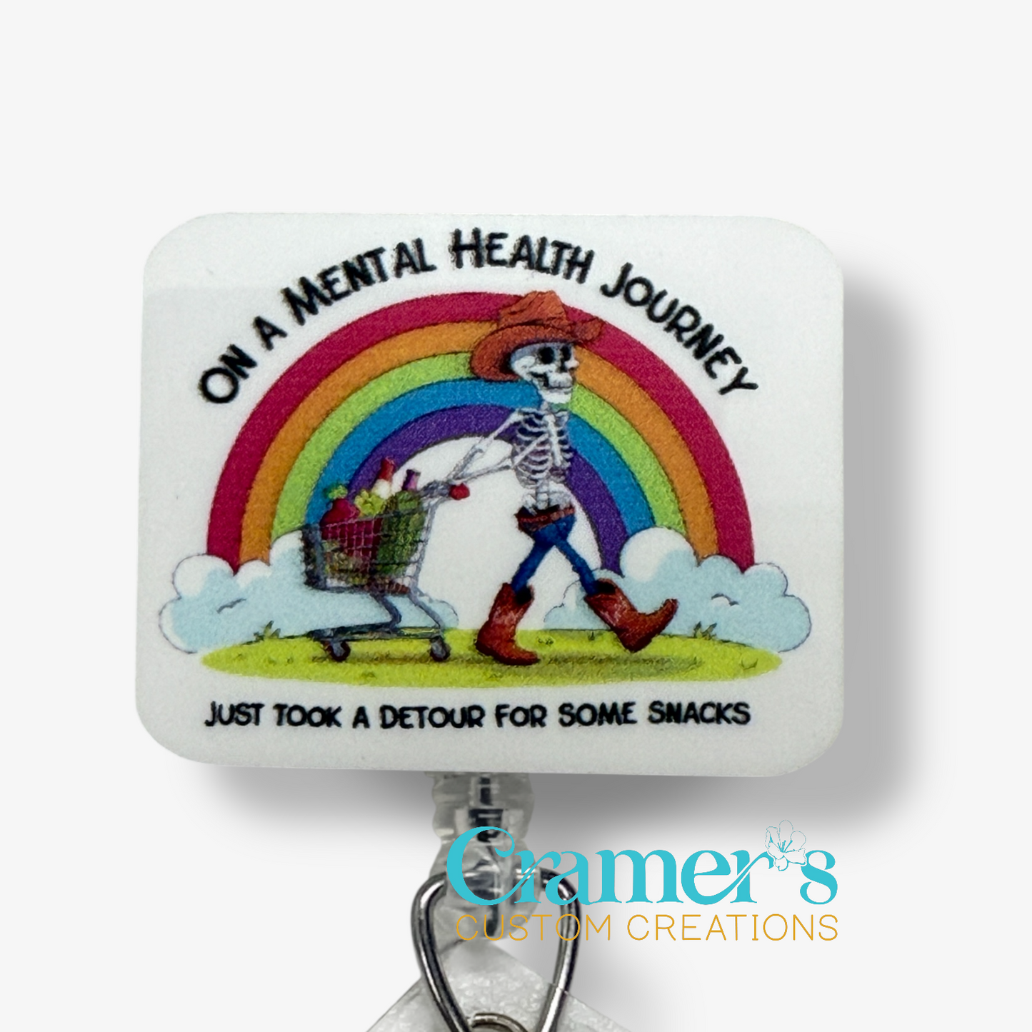 Skeletal figure with a shopping cart under a rainbow, text 'On a Mental Health Journey, took a detour for snacks', Cramer's Custom Creations logo.
