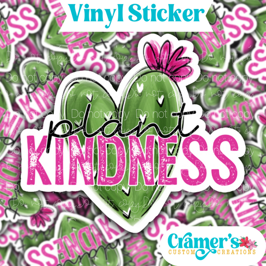 Sticker laying flat that says plant kindness with a heart shaped cactus on a background of the same sticker stacked up