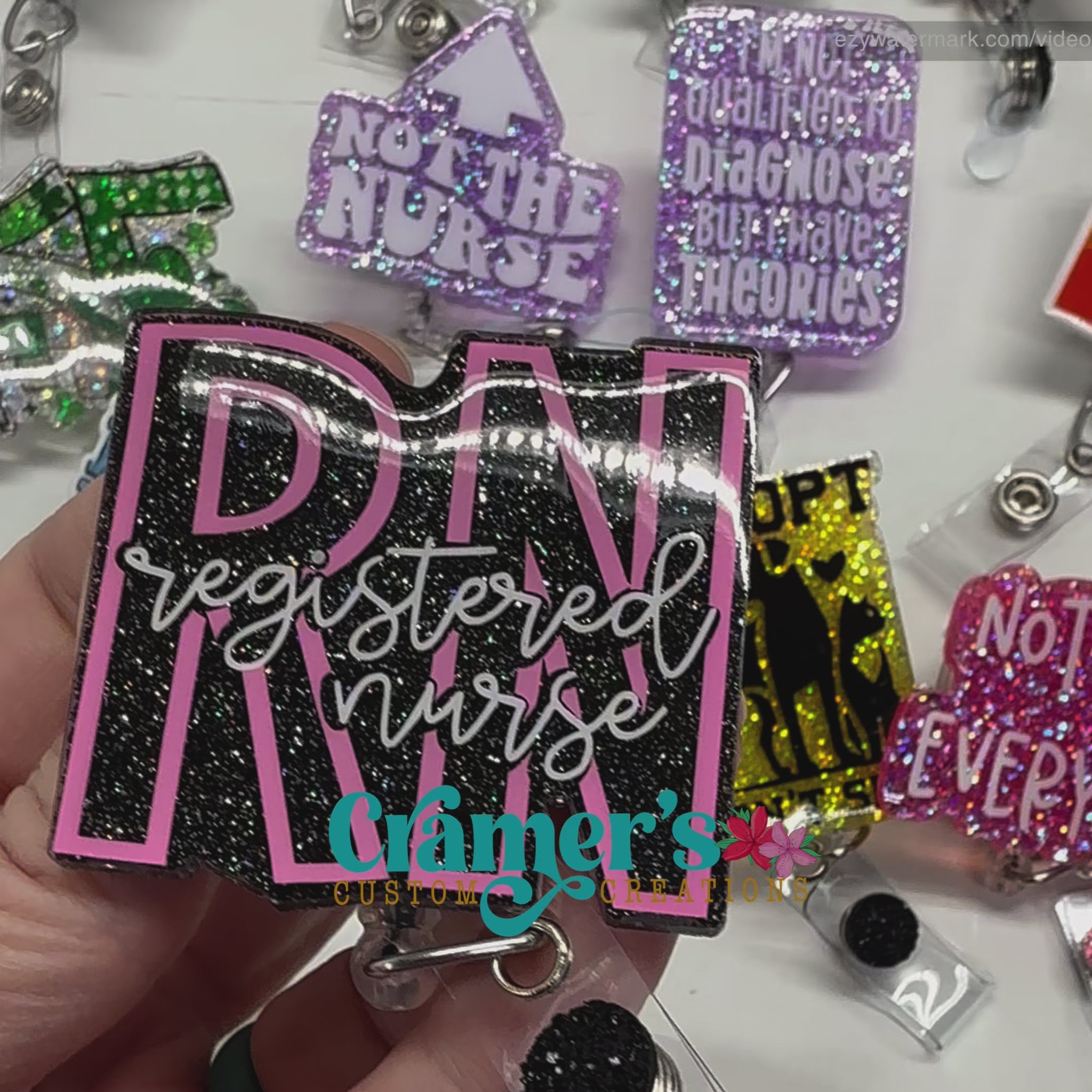 video of badge reel showing a black glitter background with the initials in pink and registered nurse in white 