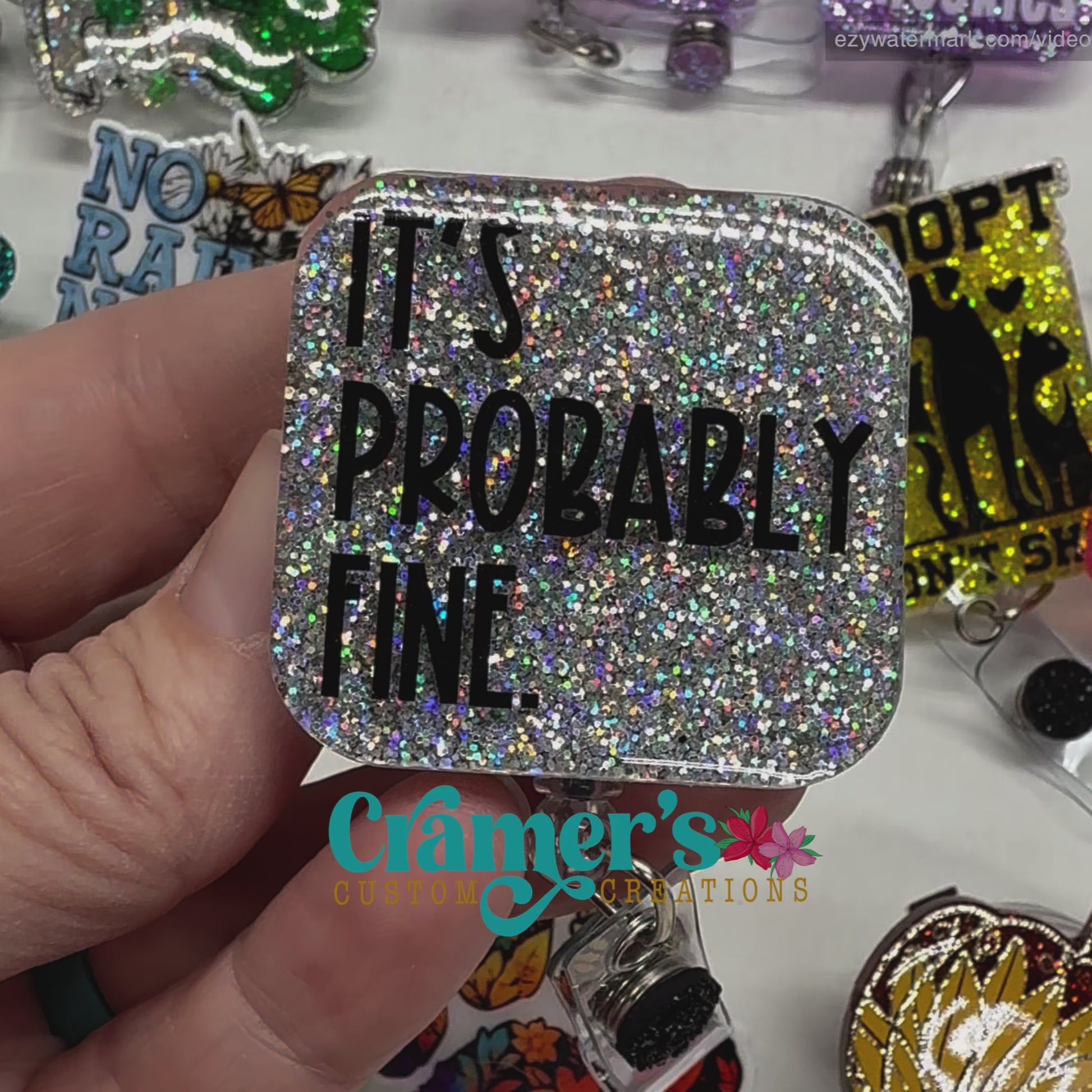 video of a badge reel showing a silver glitter background with It's probably fine in black