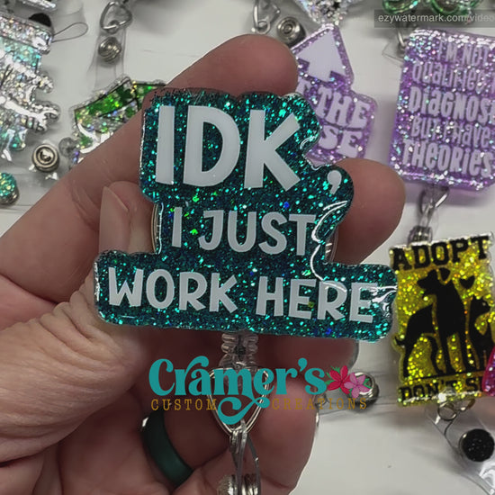 video of badge reel showing a teal glitter background with idk, i just work here in white