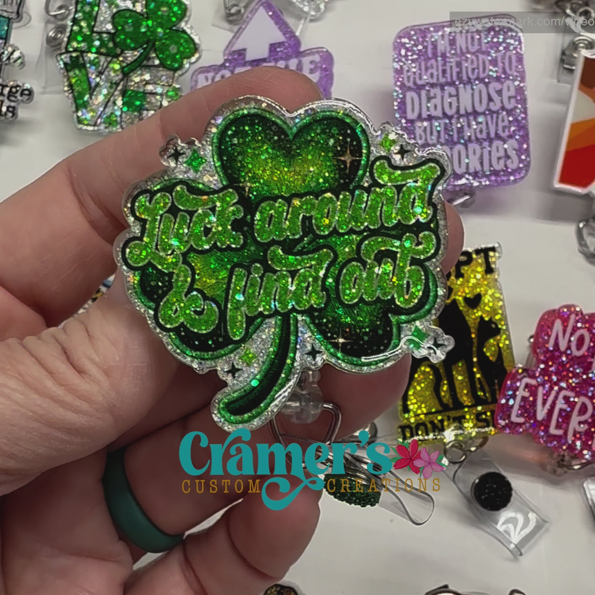 Video of 2 badge reels showing a glitter and a non glitter option of a shamrock that says luck around and find out