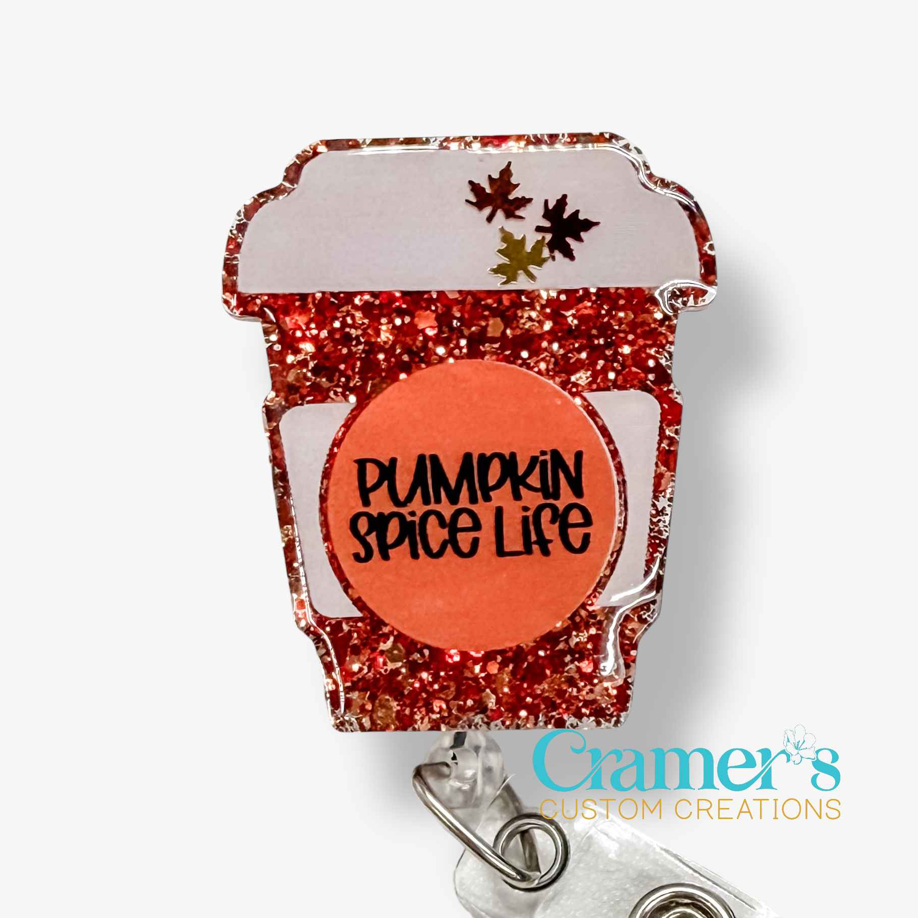 Glittery red coffee cup-shaped badge holder with 'Pumpkin Spice Life' text on a white background, featuring Cramer's Custom Creations logo.