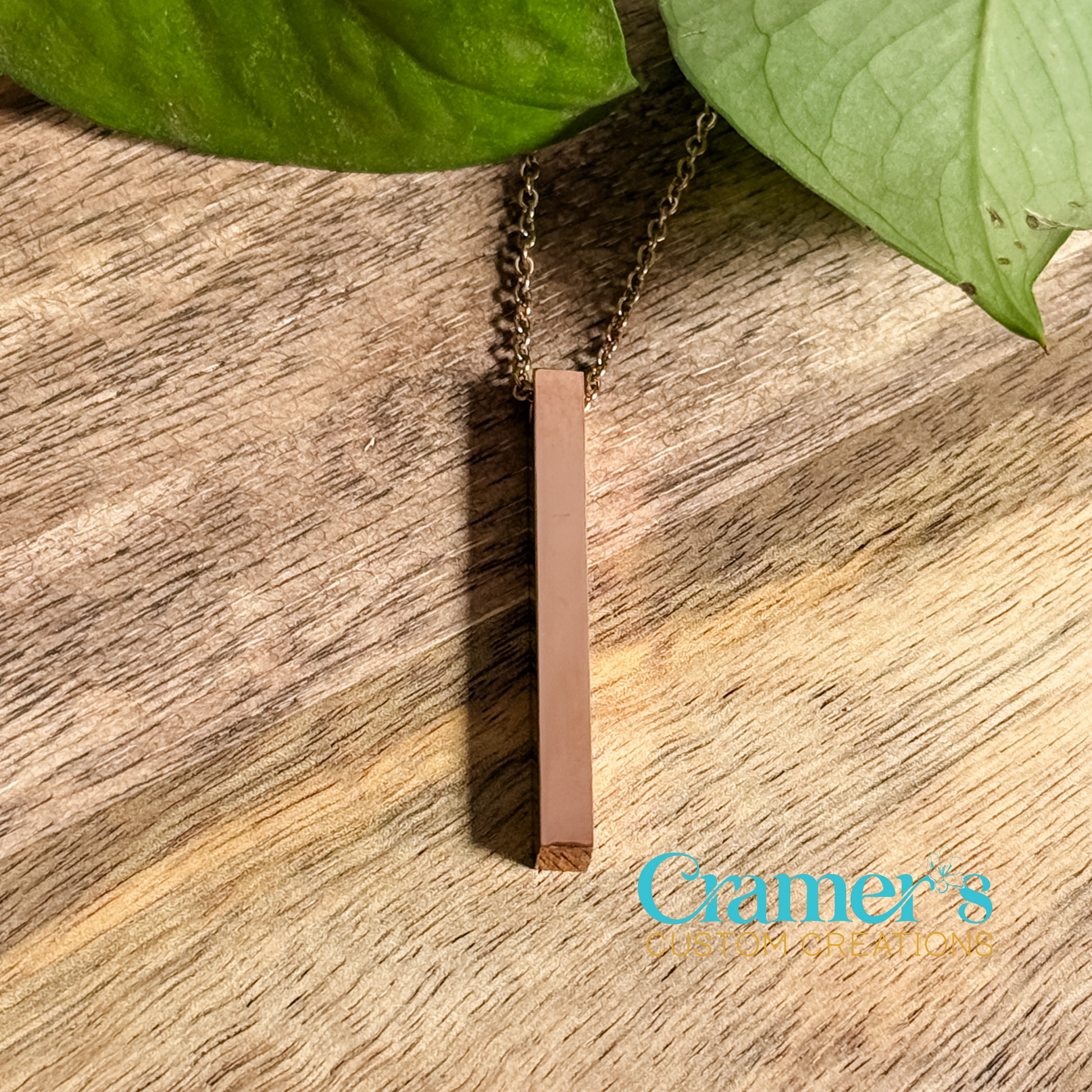 a rose gold vertical bar necklace on a wood background
