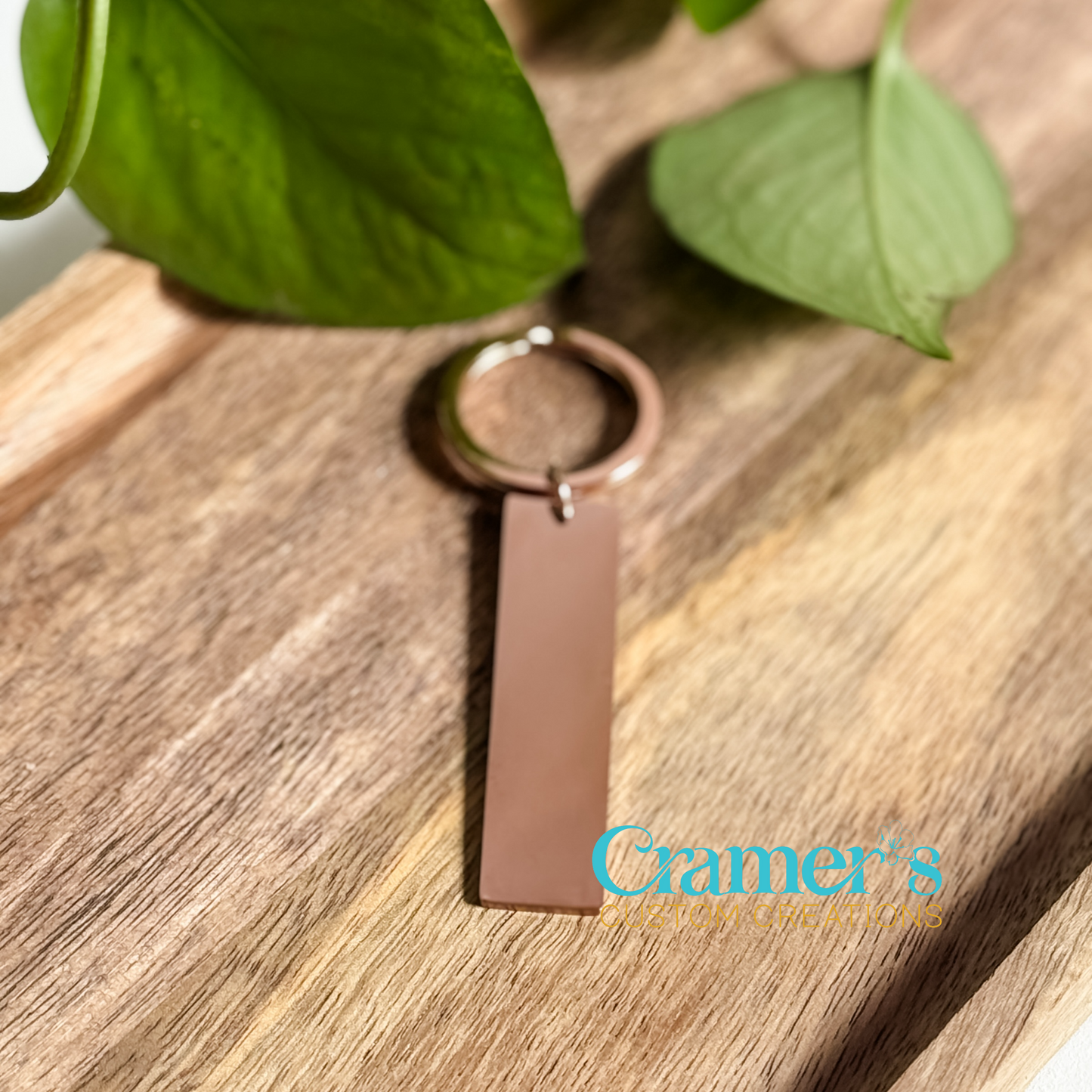 a rose gold rectangle keychain on a wood background