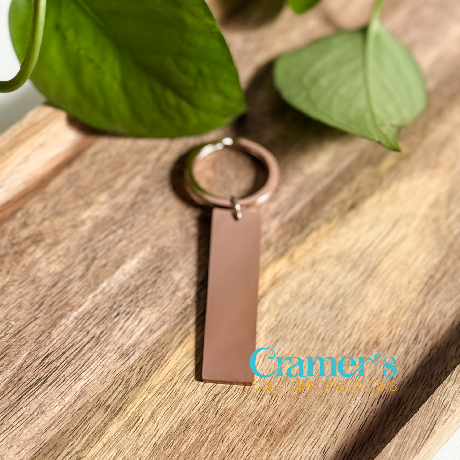 a rose gold rectangle keychain on a wood background