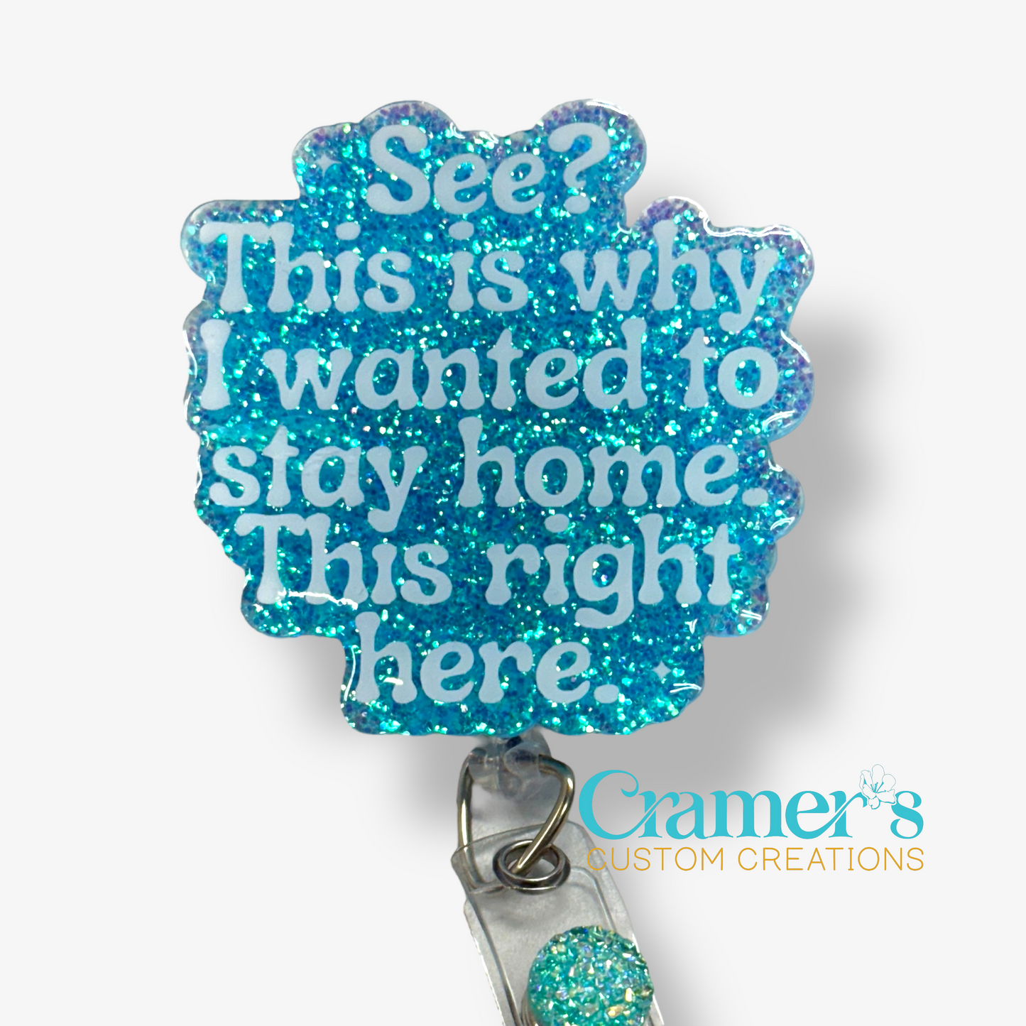 flat lay of blue glitter badge reel with see? this is why I wanted to stay home. this right here in white