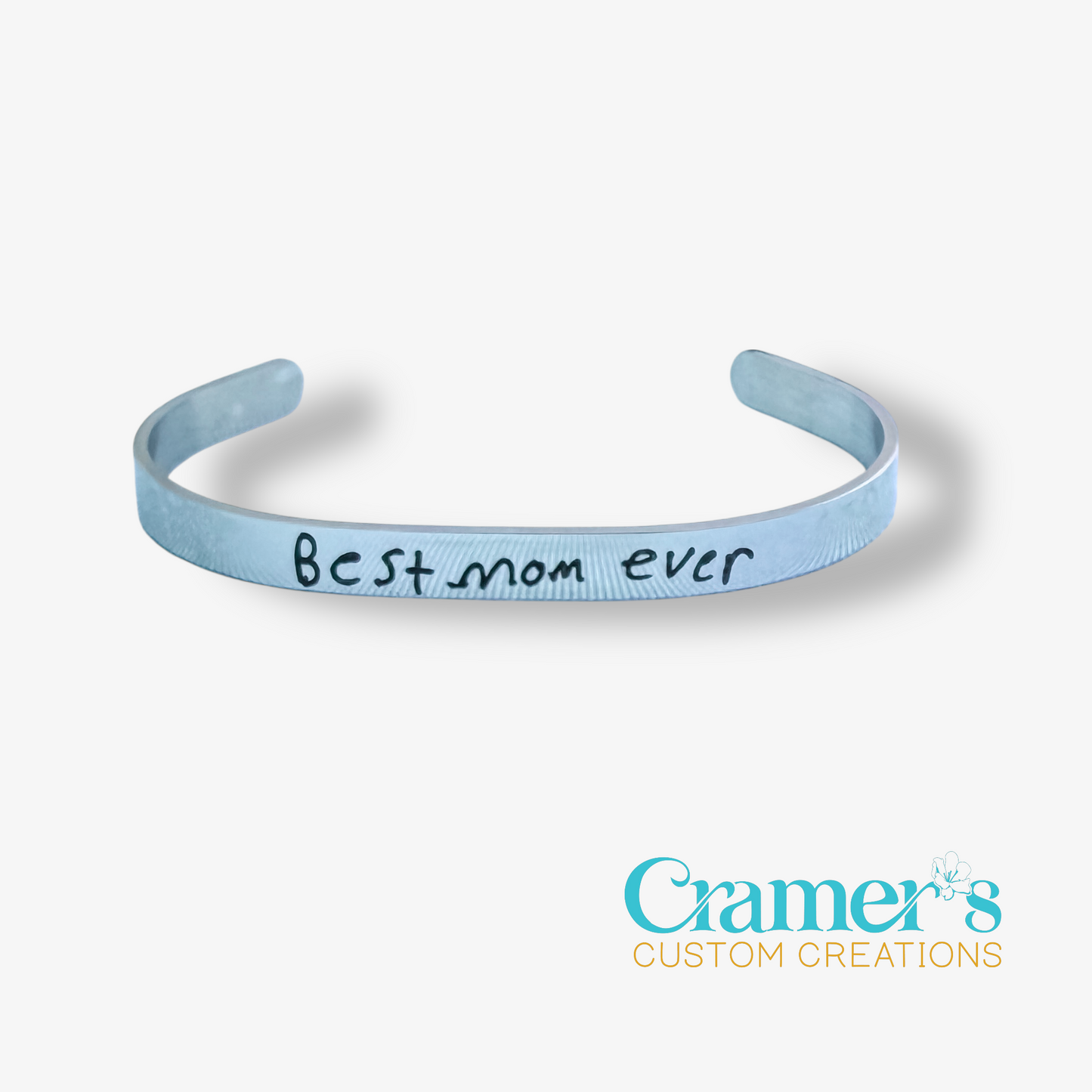 silver bracelet with 'Best mom ever' text on a white background, featuring Cramer's Custom Creations logo.