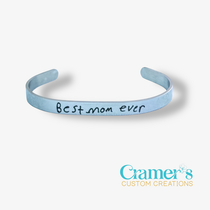 silver bracelet with 'Best mom ever' text on a white background, featuring Cramer's Custom Creations logo.