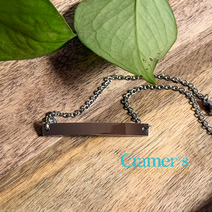 a silver bar bracelet on a wood background