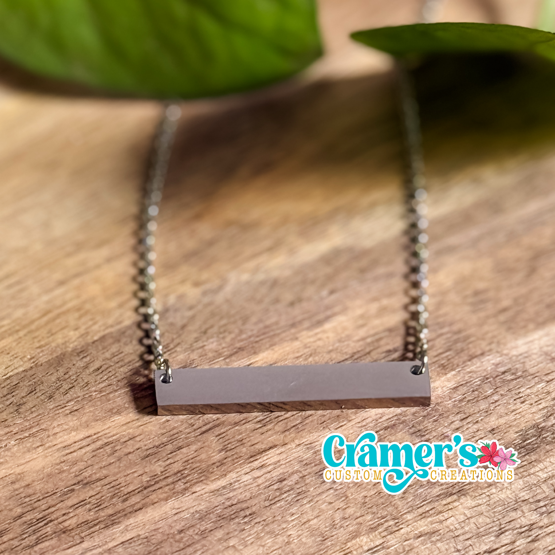 a silver horizontal bar necklace on a wood background